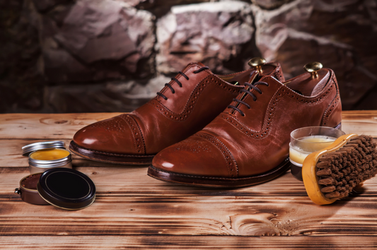 A pair of brown shoes and a brush neatly placed on a wooden table, ready for a polished look.