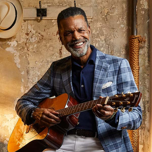 man wearing blue checked blazer and holding a guitar