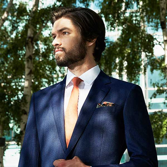 man wearing navy suit with coral tie outside
