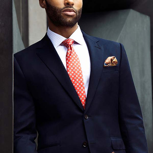 man wearing navy suit with orange tie