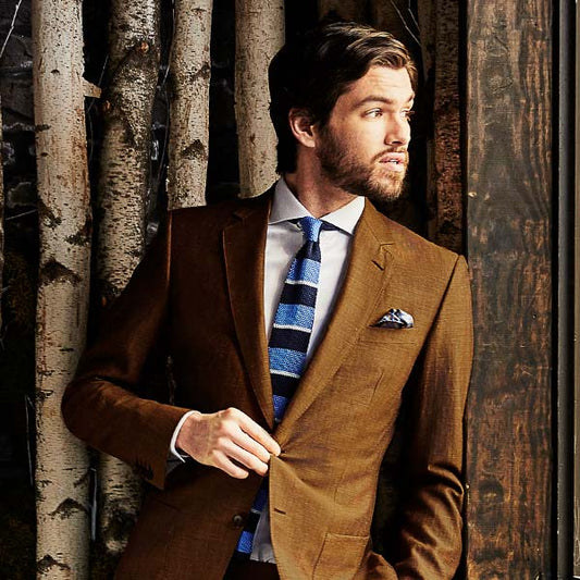 man wearing a brown suit against a rustic wooden wall