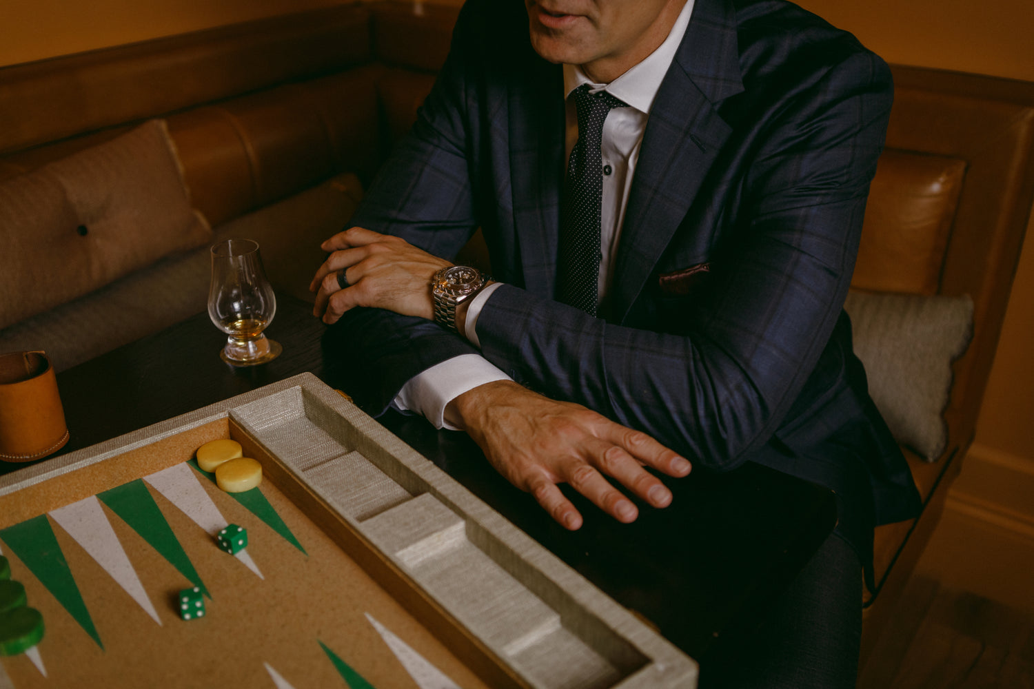 Man in a suit playing backgammon in a dimly lit room.