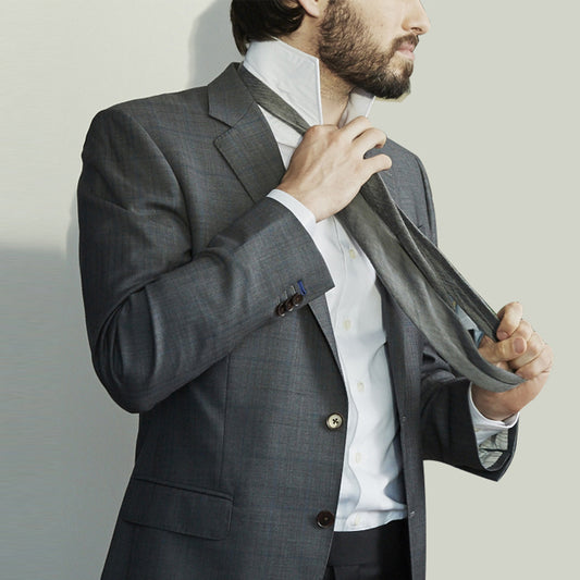 man putting on a gray tie with gray suit